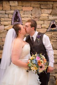 couple kissing with brightly colored wildflower bouquet