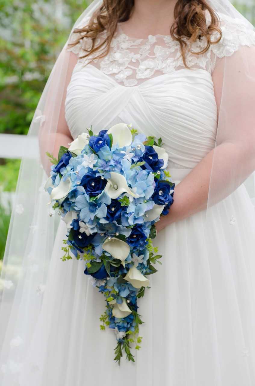 bride holding a blue cascade bouquet of roses hydrangeas and calla lilies